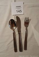 Three-piece set showing a spoon, dinner knife, and dinner fork on a white background with MaxSold lot number tag.