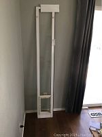 Full view of the sliding glass door insert with doggy door near bottom, standing vertically against a wall.