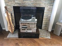 Stacked setup with Technics turntable atop Sansui cassette deck, Akai tuner, Kenwood receiver in front of fireplace