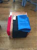 Photo showing the four silk fabrics neatly stacked highlighting the colors red, peach, black, and blue.