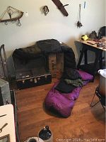 General photo showing a sleeping bag laid out on floor with other camping gear around.