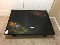 Top view showing the rectangular black low table with floral painting and abalone inlay.