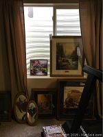 Six pieces of wall art and mirrors arranged near window and floor. Large Thomas Kinkade framed print prominently displayed.
