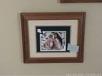 Framed Maija artwork featuring a Native American woman next to a cougar, in wood grain frame with double matting.