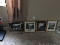 Four framed Thomas Kinkade prints leaning against a wall, with varying frame colors and sizes, clearly showing the grouped lot contents.