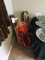 Wooden sled with red fabric seat next to a dining table with glass and metal dishes.