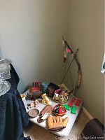 Overview of vintage adding machine, baseball gloves, costume jewelry basket, decorative bow and arrow, felt hat, castanets, and various figurines on table