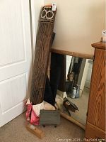 Full-length view of koto leaning against door with carrying case and stand visible