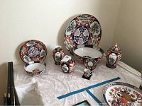 Eight-piece grouping arranged on table showing charger, large bowl, small plate, small bowl, vase, jar, cup and saucer