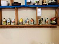 Shelf display showing all 9 bird figurines in a wooden cubical shelf, each approx 4 inches tall, detailed and colorful.