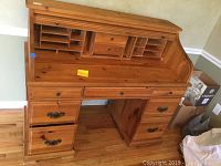 Front view of pine roll-top desk with tambour top open showing interior cubbies and drawers