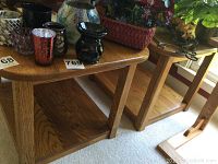 Pair of matching solid wood end tables with rectangular tops and lower shelves; wood grain clearly visible and tables situated on carpeted floor.