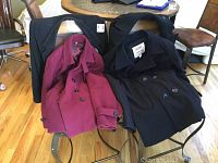 Four wool coats displayed over chairs showing different colors and styles.