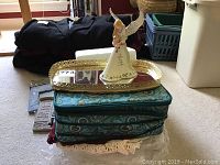 Overview of lot items stacked including jewelry case, mirror tray, ceramic music figurine, and crochet dollies underneath