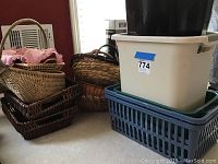 Photo showing grouped wicker baskets including rectangular and oval shapes with some liners, and several stacked plastic waste baskets in various colors and sizes.