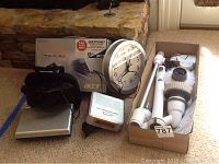 Photo showing Acer Aspire One laptop with box, Audiovox LCD monitor/DVD player, wall clock, clock radio, and TurboScrub 360 power scrubber parts in a box.