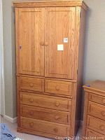 Front view of the entire wood armoire cabinet showing closed double doors and drawers below.