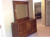 Full view of the wood dresser with the attached matching framed mirror placed on top, showing the front and side profile of the furniture.