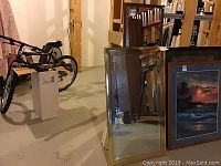 Two framed rectangular wall mirrors leaning against a wooden frame in a basement. One mirror smaller (41.5x23.5) and one larger (55x15.5). One frame shows need for repair.