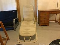 Overall front view of beige fabric lounge chair with metal frame on concrete floor near wooden furniture.