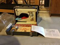 Viking Model 6030 sewing machine in carrying case with accessories and manual placed on table.