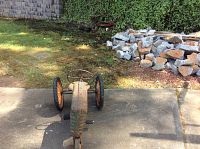 Top front view of the vintage toy tractor and wagon in backyard with stone pile and ivy behind