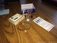 Overview on wood table showing all rings, earring, pin and cuff bracelet
