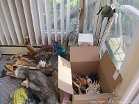 Overview showing heron statue, manatee figure, wooden fish and pelican sculptures, and box of small items