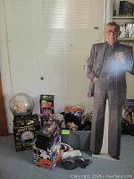 Photo showing George Burns standee, Spirit Ball box, and bin filled with Halloween masks in front of closet doors.