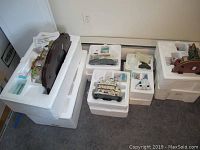 Photo showing multiple holiday-themed sculptures including village pieces and sculptures packed in white Styrofoam boxes.