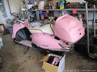 Left side view of pink IL Bello scooter with removable trunk in garage