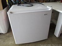 Closed frontal view of compact white Kenmore dorm fridge showing some dents and overall condition.
