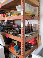 Shelf with assorted tools including drills, vise, socket set, and toolboxes packed on multiple levels