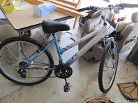 Full profile side view of RoadMaster women's mountain bike, light blue frame with purple accents, showing tires, seat, pedals, and handlebars.