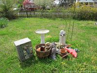 Photo of the full set on a lawn showing birdbath, statues, basket with pots and flamingo.