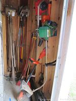Photo showing gas powered Weed Eater string trimmer, leaf blowers, and electric trimmers hanging on wall