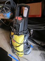 Front view of the yellow and black Karcher pressure washer with power cord wrapped around it.