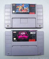 Front view of two Super Nintendo game cartridges showing the label artwork for Art of Fighting and Joe & Mac.