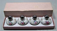 Box with two sets of 4 ceramic salt and pepper shakers resting inside compartments of original pink textured box.