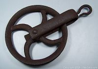 Front view of the cast iron pulley showing the wheel and hook detail with rusted, aged metal surface.