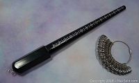 Plastic black ring sizing mandrel with white markings on a light background