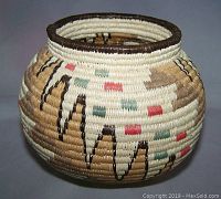 Close front view of the round handwoven vintage grass basket with zigzag patterns and colored accents.