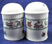 Front view of the two salt and pepper shakers showing Pooh and Tigger on one shaker, and Piglet and Eeyore on the other, with leafy decorative pattern.