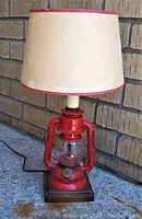Front view of the red Dietz Ranch Craft lantern converted to a lamp with beige shade, showing the overall lamp height and condition.