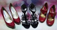 All three pairs of high heeled shoes: red Steve Madden patent pumps, black strappy sandals, and red Mary Jane heels