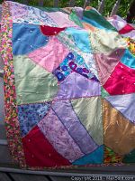 Quilt showing the colorful patchwork patterns with hand-stitched embroidery and floral border.