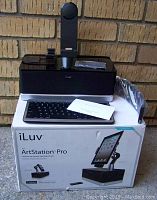 Speaker dock, Bluetooth keyboard, remote control placed on top of white box with product branding and specs.