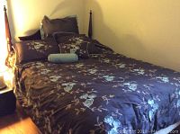 Full view of queen size cherry wood poster bed with floral linens and pillows, showing the headboard and posts