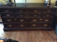 Photo showing front view of the ten drawer dresser with brass drawer pulls and dark wood finish.