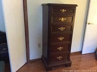 Front view of tall six drawer dark wood lingerie chest with brass hardware